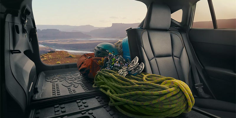 View from the car's trunk showing a river and canyon, with climbing gear in the cargo area.