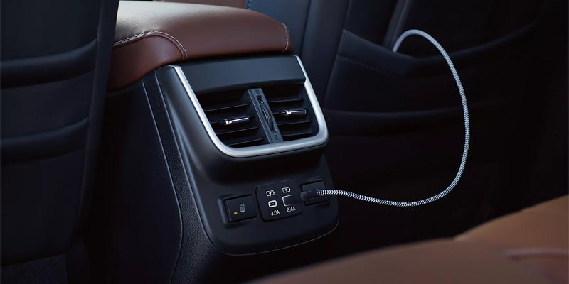 Rear console with HVAC vents, two USB ports, and a heated seat button; a charging cable is plugged in.