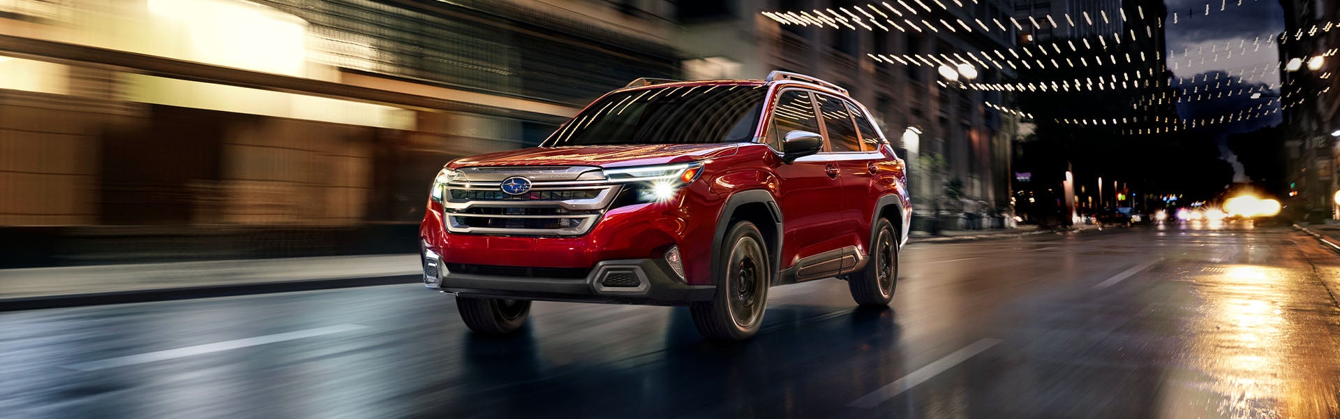 Red Subaru Forester driving through a city at night.