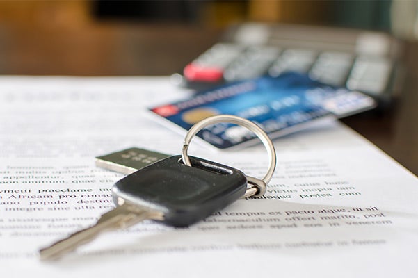 A car key and a credit card on a document with text, suggesting car finance or purchase.